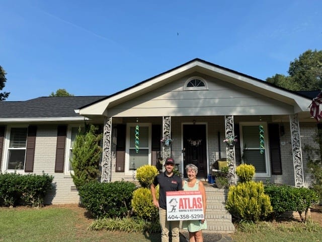 Atlas Roofing & Restoration owner and homeowner posing with Atlas sign in front of a residential roofing project in Athens GA
