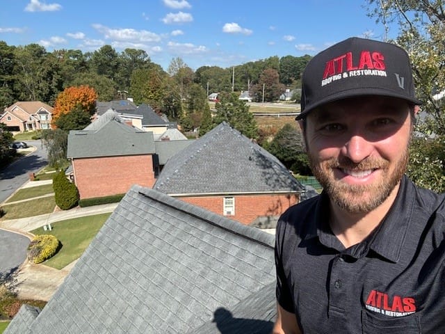 Owner of Atlas R&R showing off completed roofing projects with clear pressure washed brick